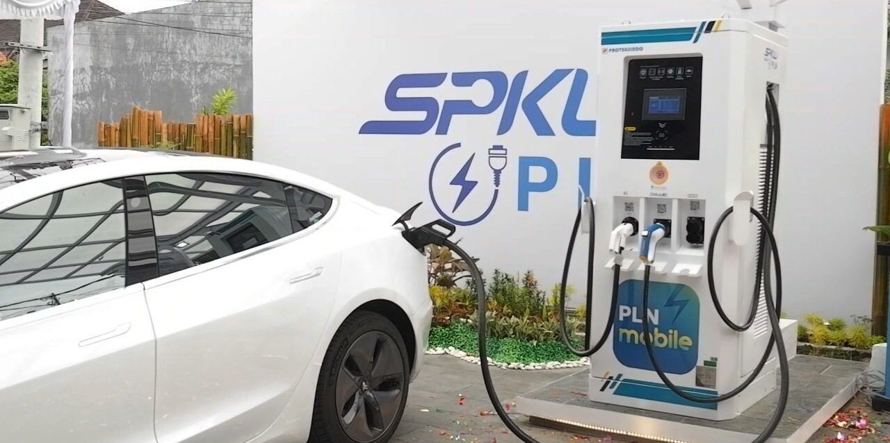 A sleek Chinese electric car charging at a Public EV Charger Station (SPKLU), highlighting Indonesia's growing EV infrastructure.