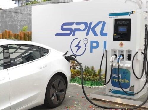 A sleek Chinese electric car charging at a Public EV Charger Station (SPKLU), highlighting Indonesia's growing EV infrastructure.