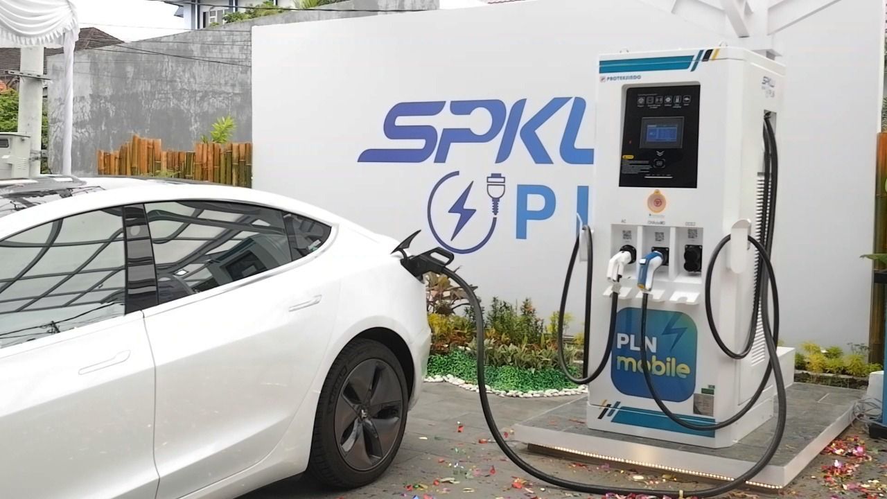 A sleek Chinese electric car charging at a Public EV Charger Station (SPKLU), highlighting Indonesia's growing EV infrastructure.